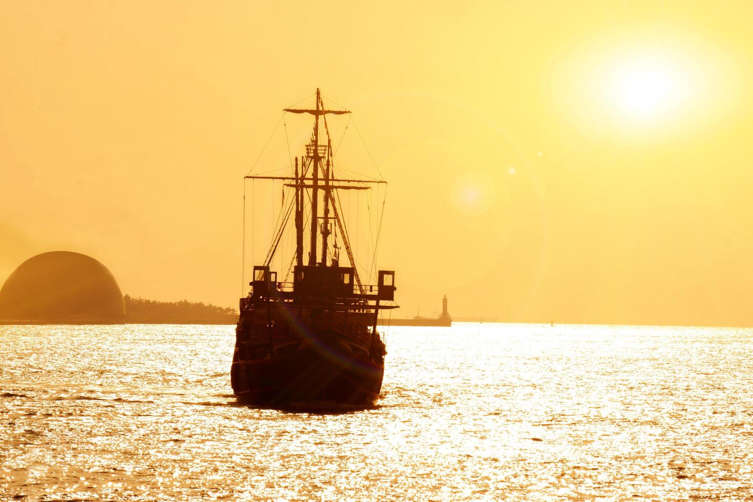 Silhouette of Santa Maria Cruises for Osaka bay sightseeing are sailing in the  evening with sun and lens flare background. photo