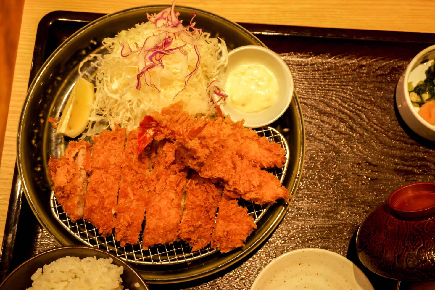 Top view Japanese food Fried pork and fried shrimp with salad a delicious food to be satisfied in yellow lights tone with on black ceramic plate, plastic tray and wooden table. photo