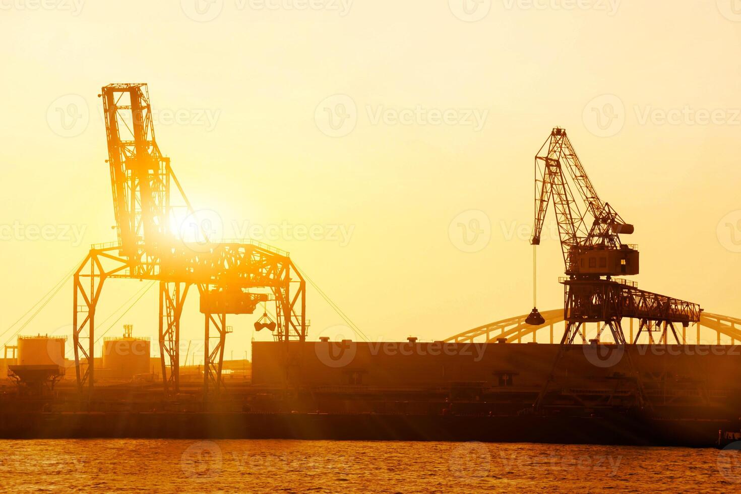 Silhouette of container crane at Osaka port are loading on evening with sunset color tone and gantry crane working background. photo
