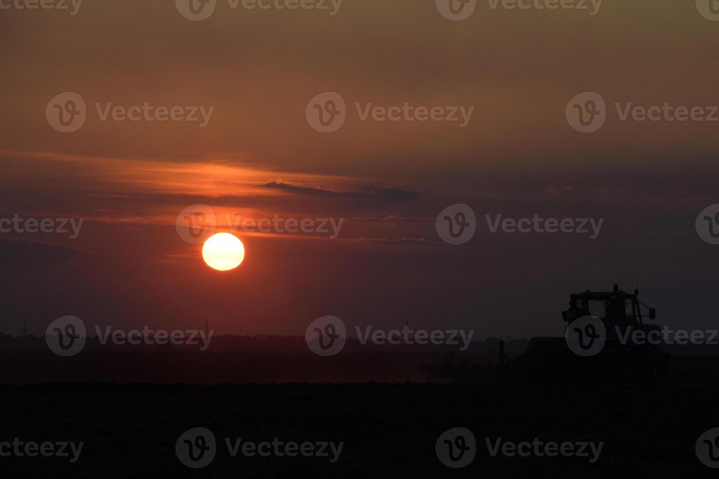 Tractor plowing plow the field on a background sunset. tractor silhouette on sunset background photo