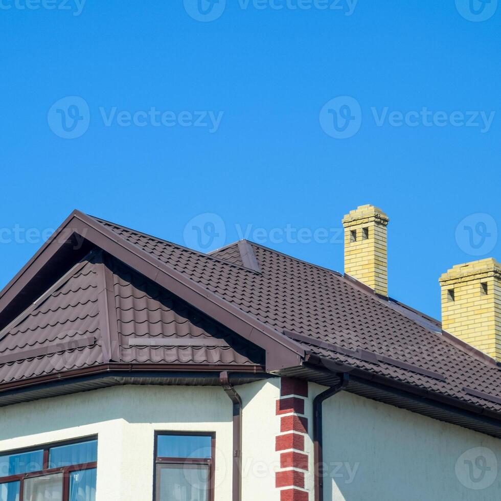 House with plastic windows and roof of corrugated sheet. Roofing of metal profile wavy shape on the house with plastic windows photo