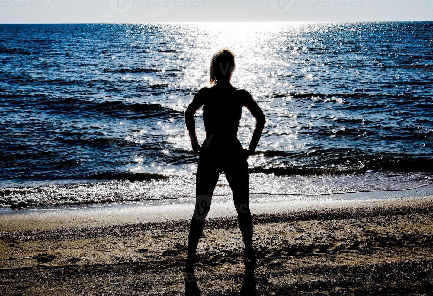 Silhouette of a beautiful girl figure on the background of the sea at sunset photo