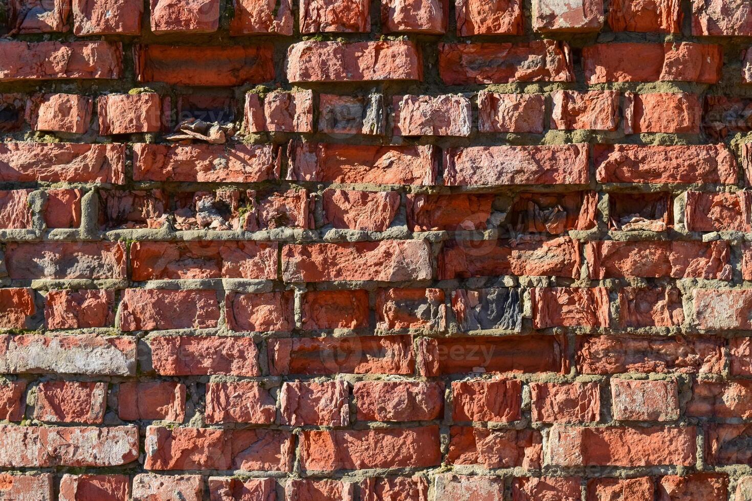 Destroyed by time and precipitation brick wall. photo