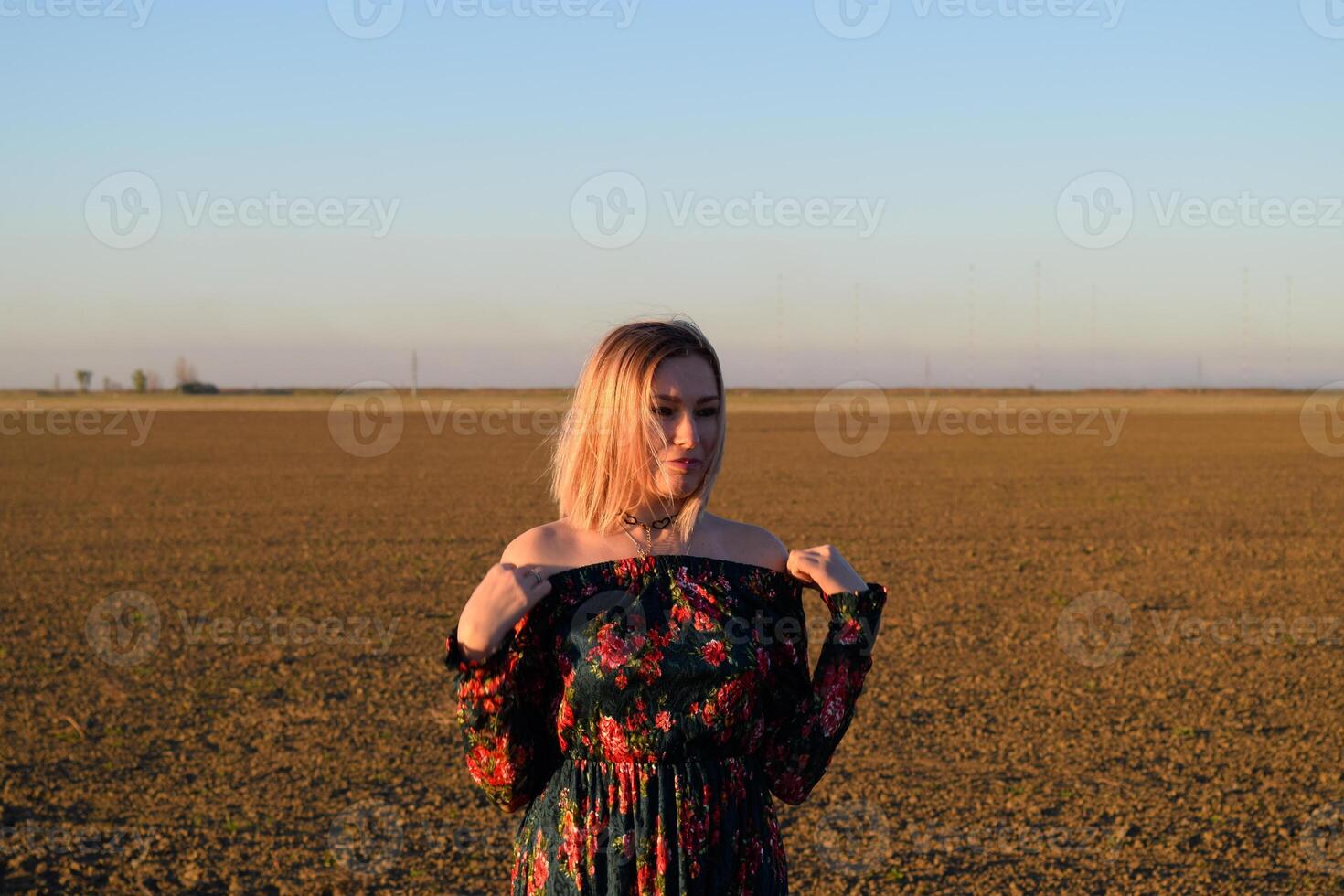 mujer en un arado campo en un negro rojo vestir en un puesta de sol antecedentes. foto