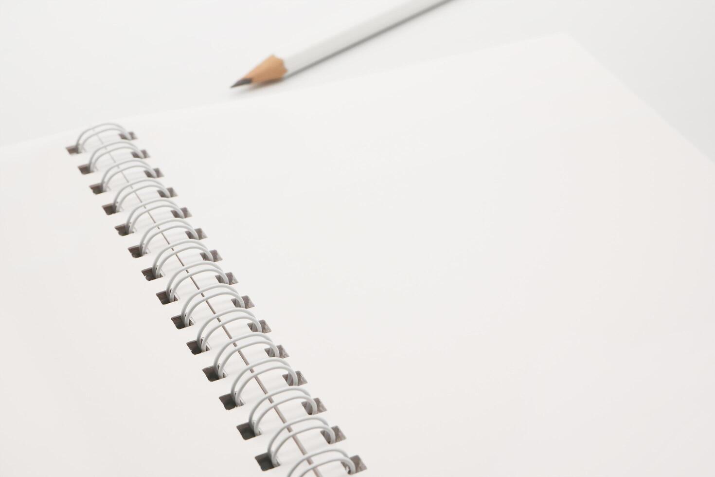 Blank white spiral notebook with white pencil on bed. photo