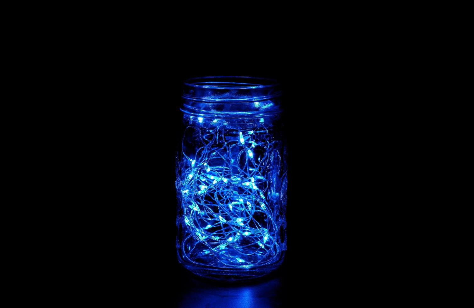 Blue fairy light in a glass jar, in the dark, low-key photography photo