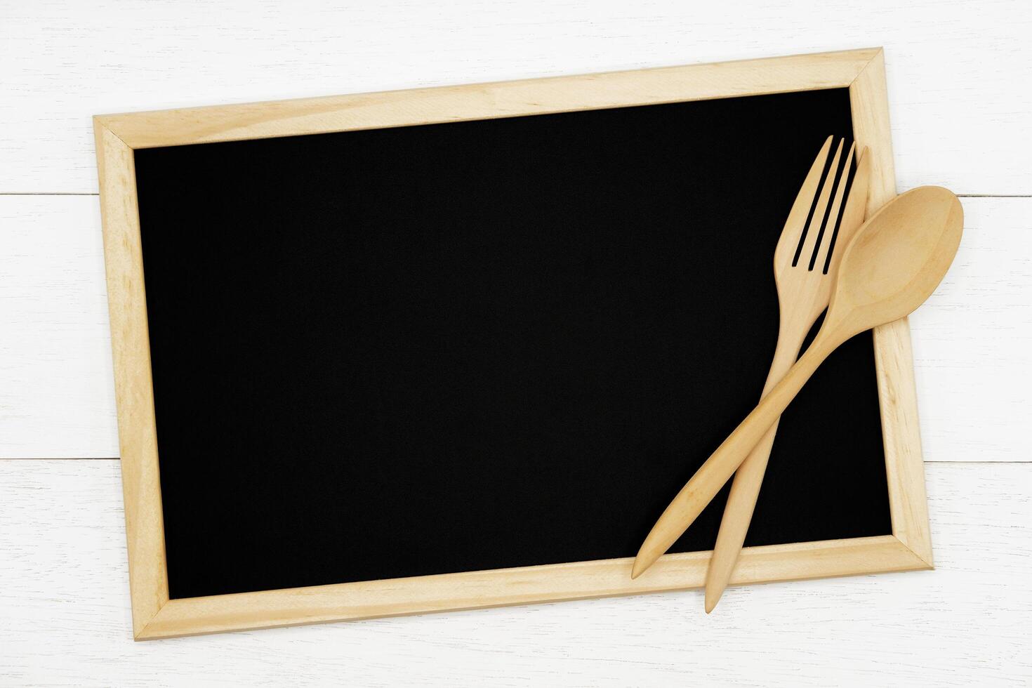 Blank chalkboard with wooden spoon and fork on white wood plank background. Styled stock photography for cookbook, food blog posts and social media content. photo