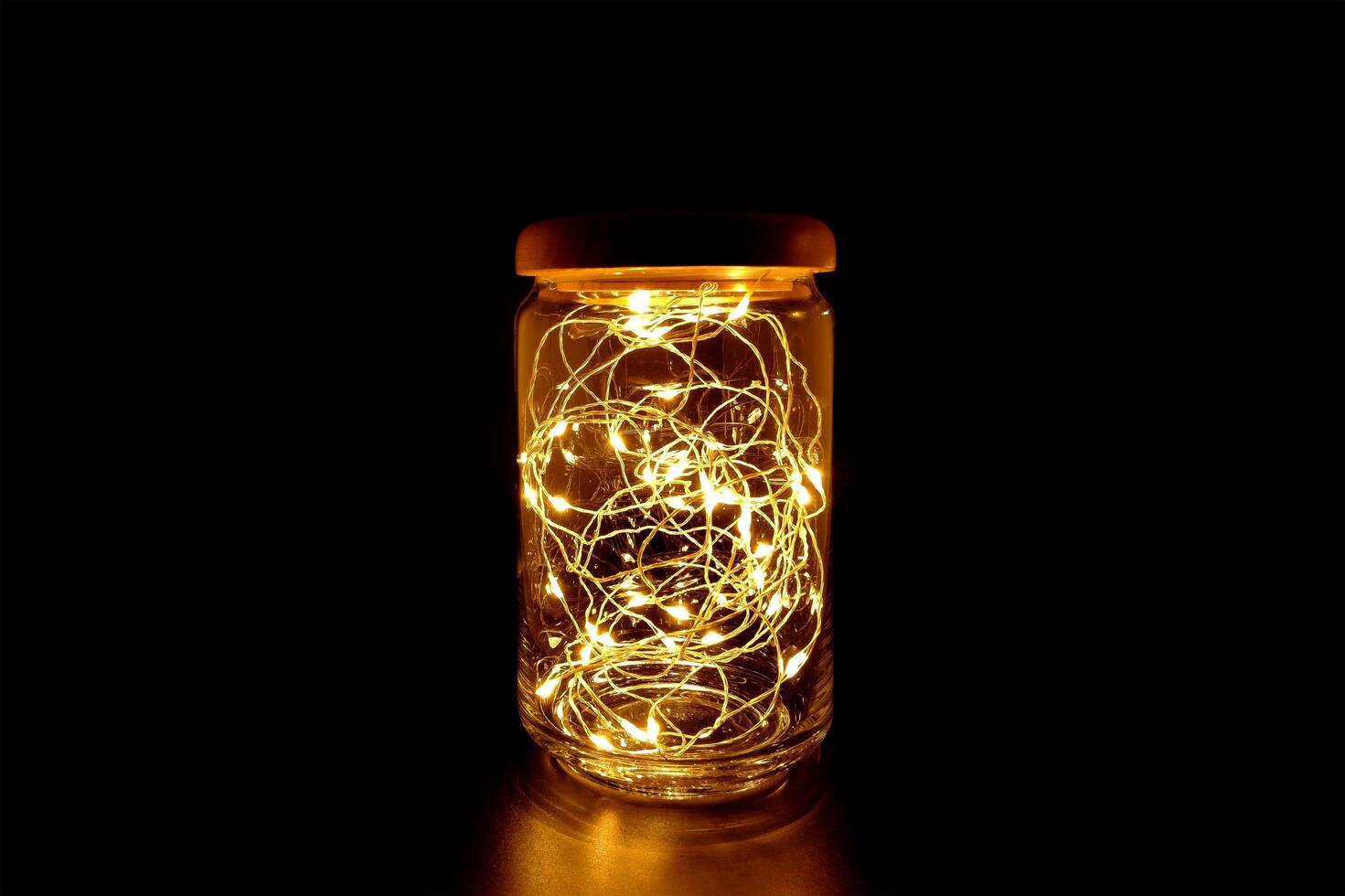 Fairy Light in a Glass Jar with Wooden Lid, in the Dark. Low-Key Photography. photo