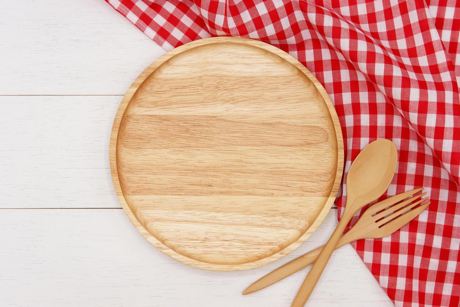 Empty round wooden plate with spoon and fork on white wooden table. Top view image. photo