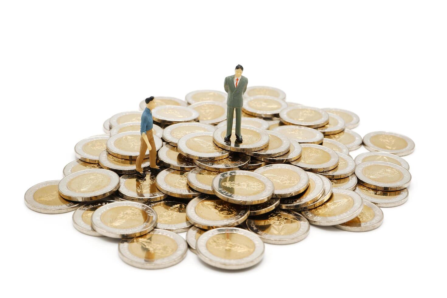 miniatura empresario en pie en pila de nuevo 10 tailandés baht monedas, aislado en blanco antecedentes. negocio concepto. foto