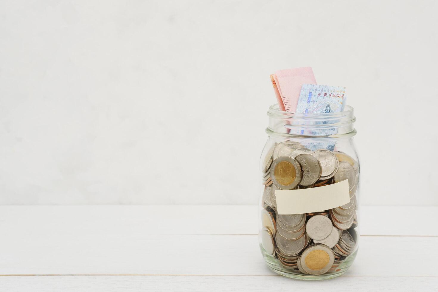 Thai Baht banknotes and coins in a glass jar. Business and finance concept. photo