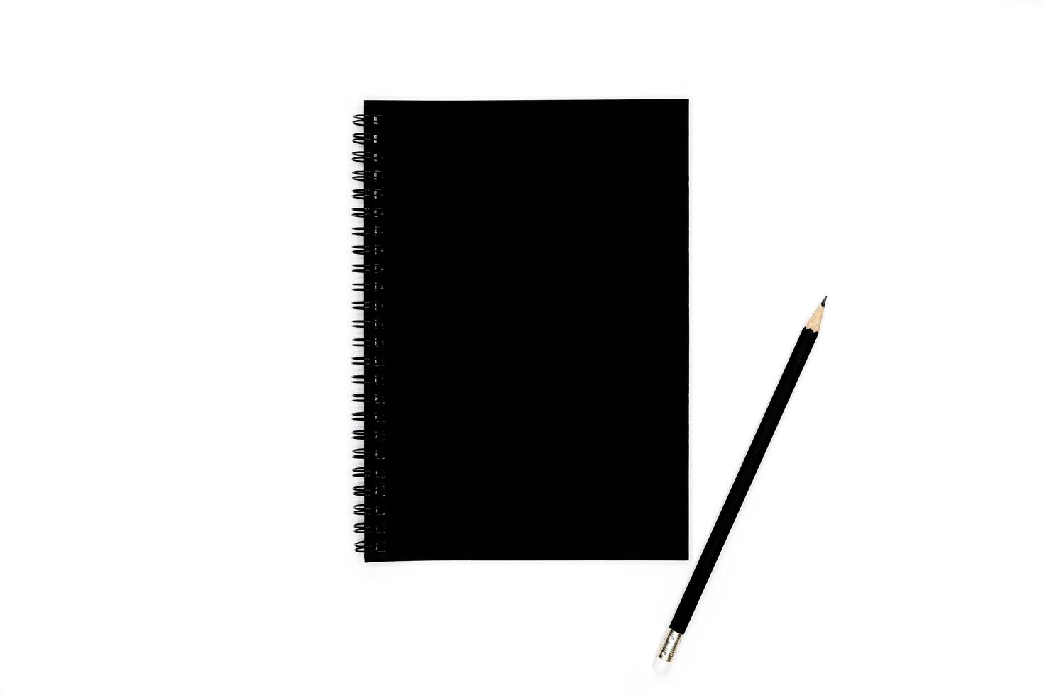Black pencils with black spiral notebook on white background. photo