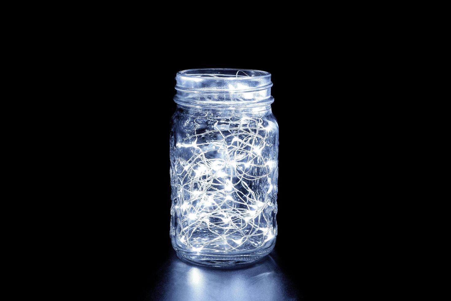 White fairy light in a glass jar, in the dark, low-key photography photo