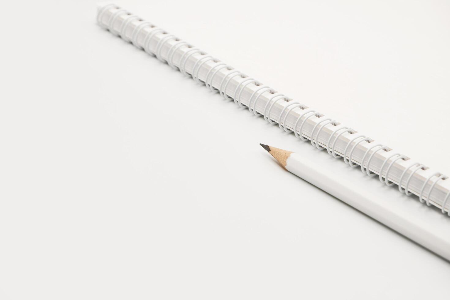 Blank white spiral notebook with white pencil on bed. photo