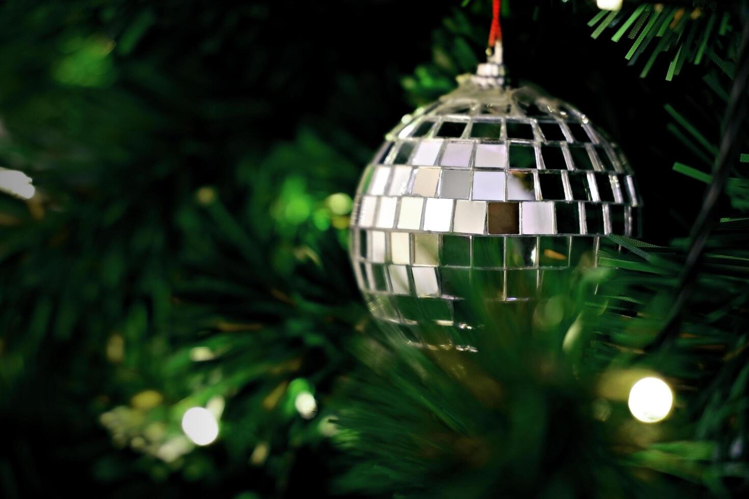 Closeup image of silver mirrored mosaic Christmas ornament hanging on Christmas tree. photo