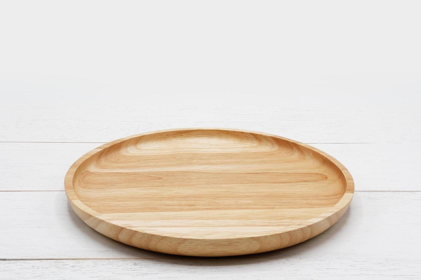 Empty round wooden plate on white wooden table. photo