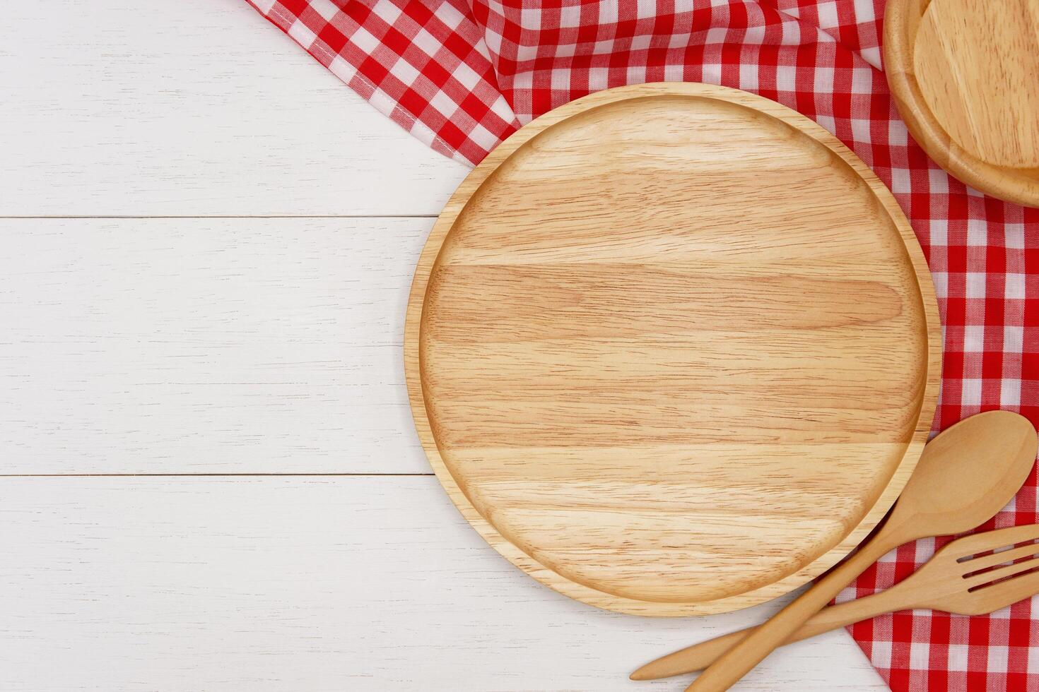 Empty round wooden plate with spoon and fork on white wooden table. Top view image. photo