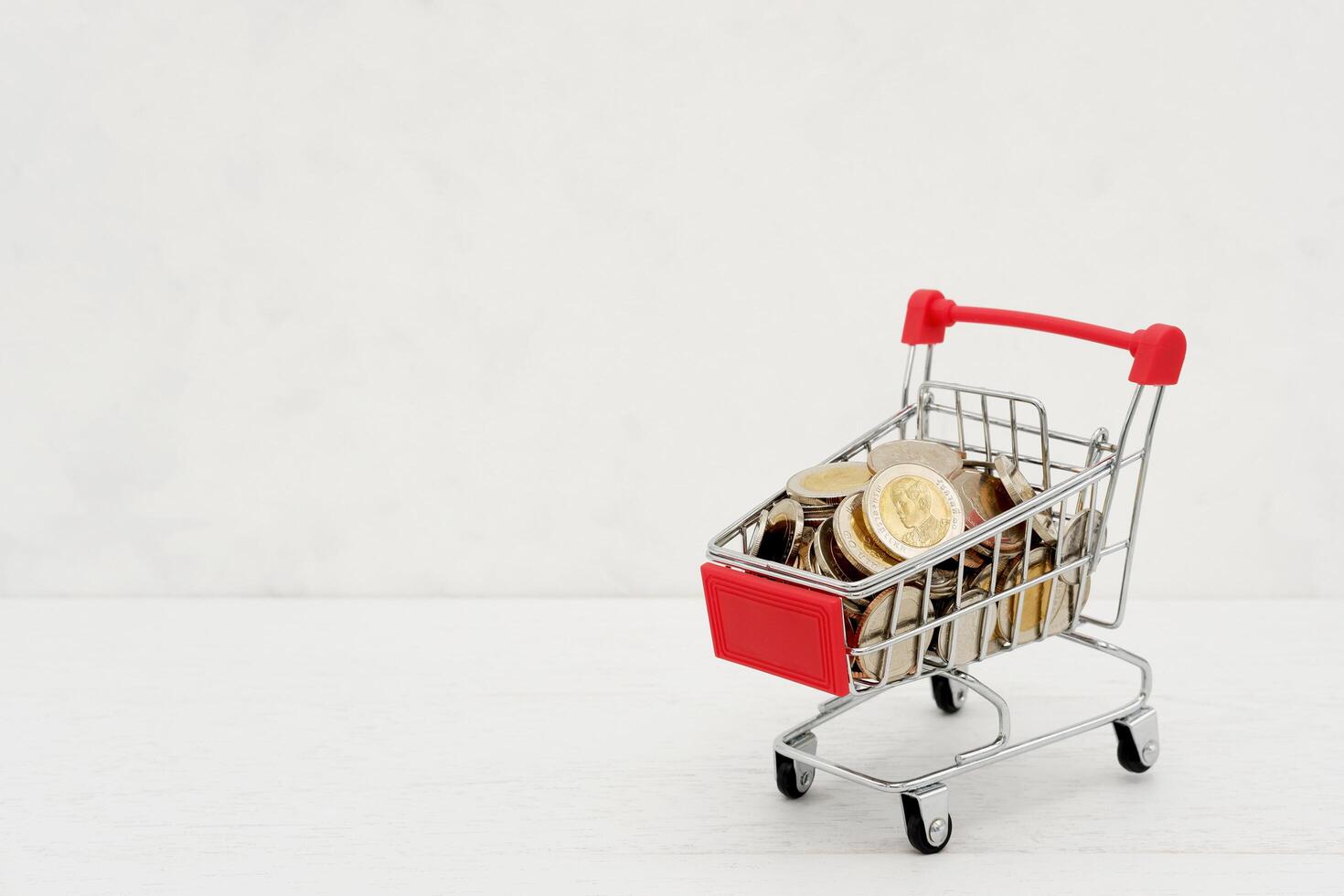 New Thai Baht coins in red miniature shopping cart. Business and finance concept. photo