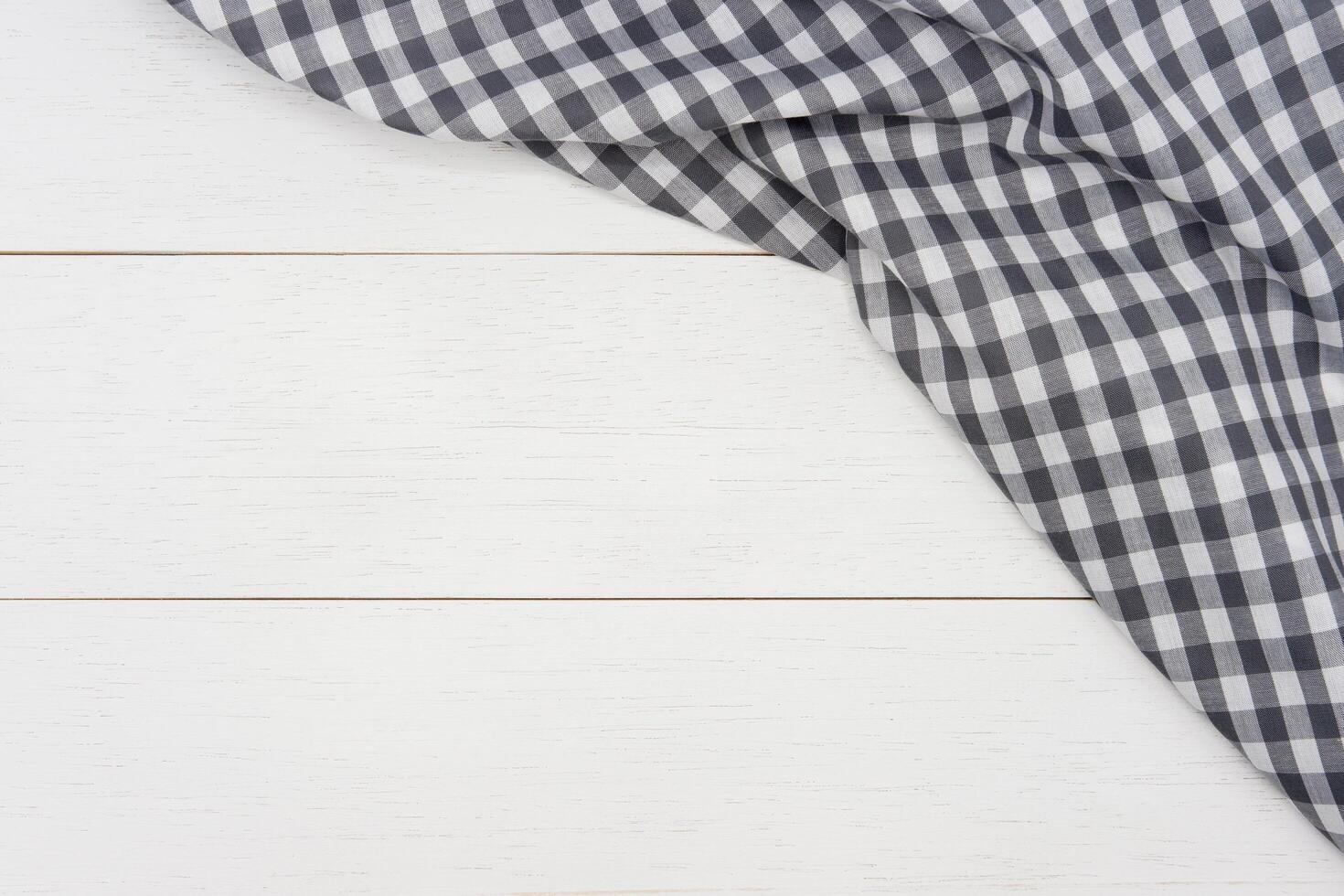 Wrinkled grey gingham fabric on rustic white wood plank background, with copy space. photo