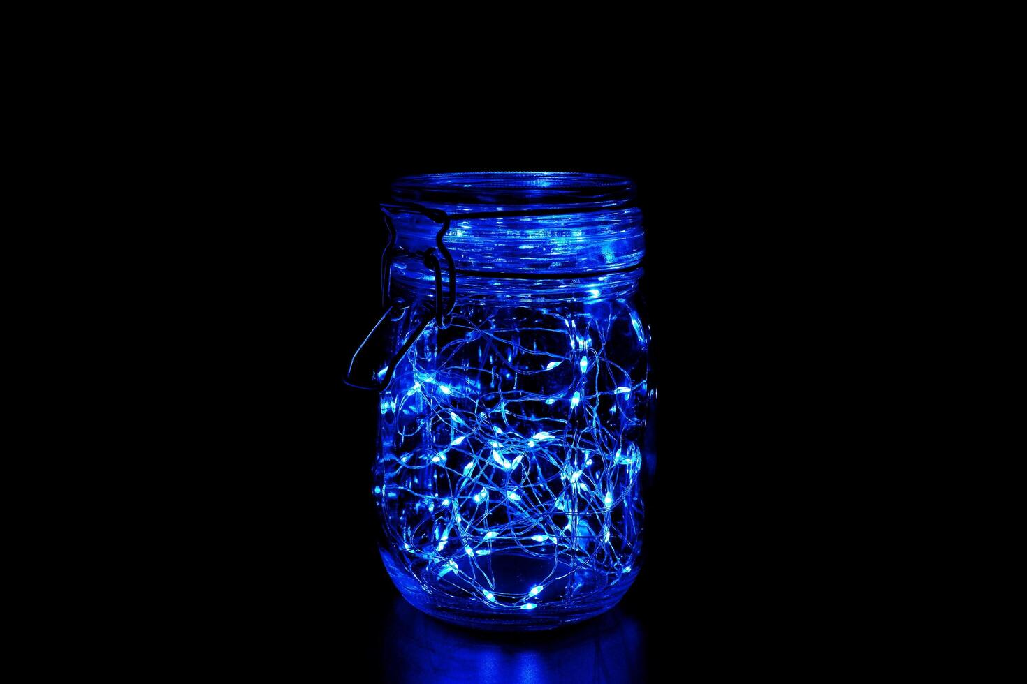 Blue fairy light in a glass jar, in the dark, low-key photography photo