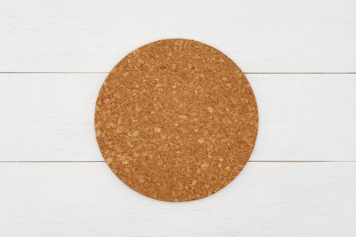 Empty round cork coaster on white wooden table. Top view image. photo