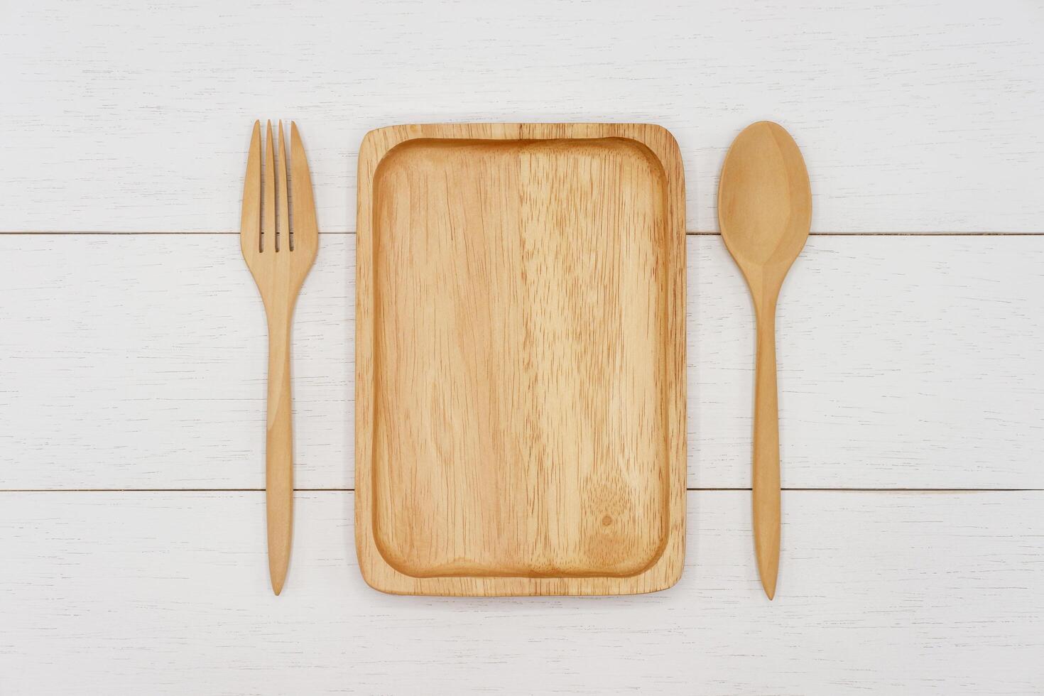 Empty rectangle wooden plate with spoon and fork on white wooden table. Top view image. photo