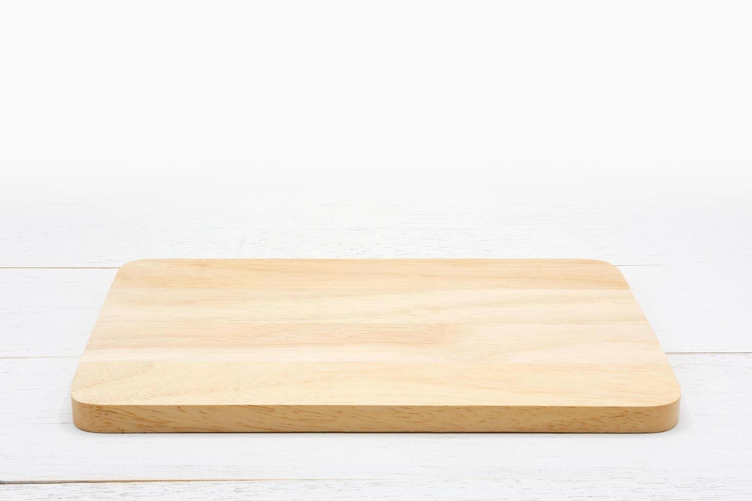 Empty rectangle wooden cutting board on white wooden table. photo