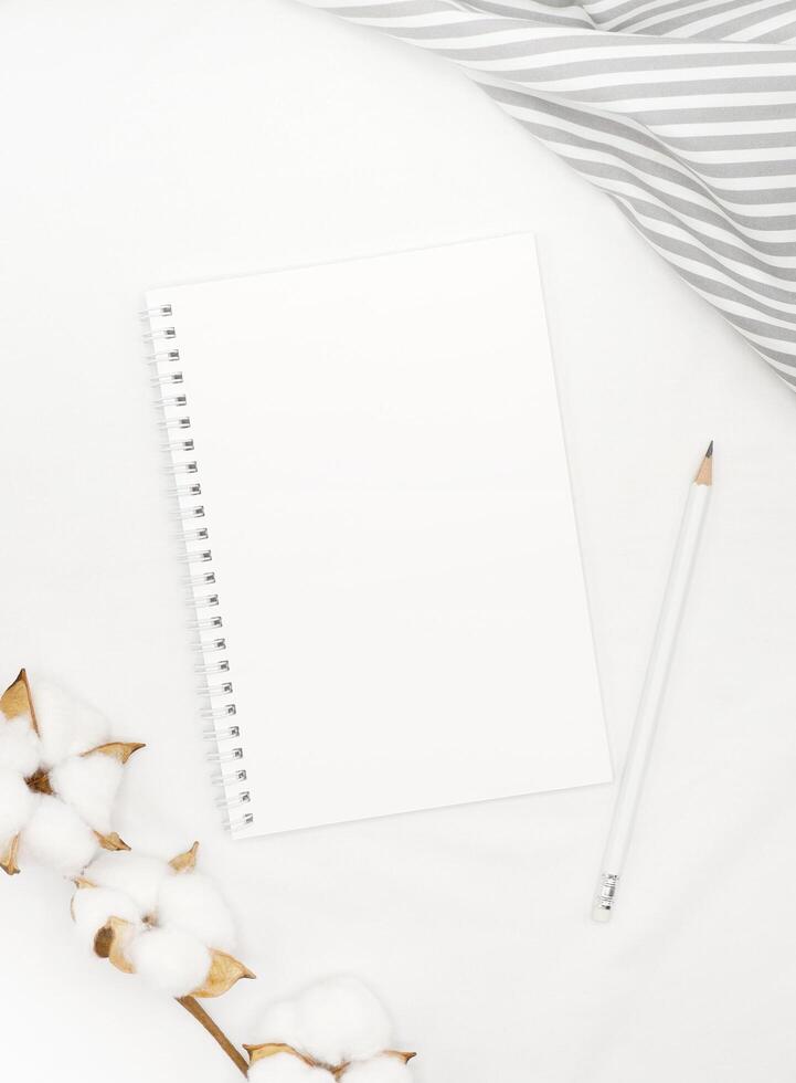 Blank white spiral notebook with white pencil on bed. photo