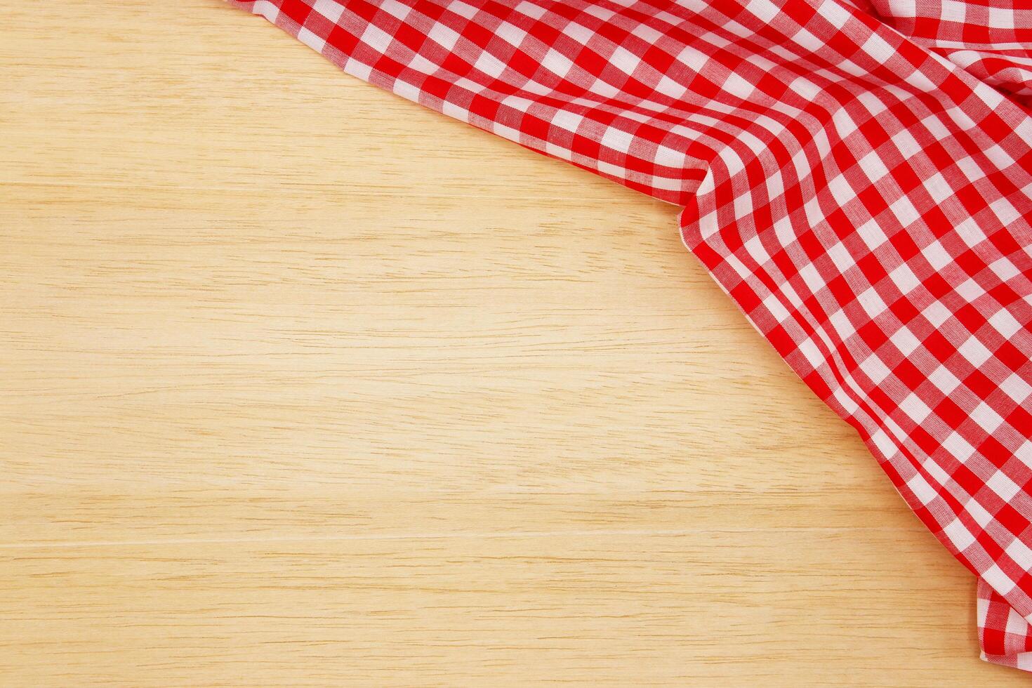 Wrinkled red gingham fabric on rustic wood plank background, with copy space. photo