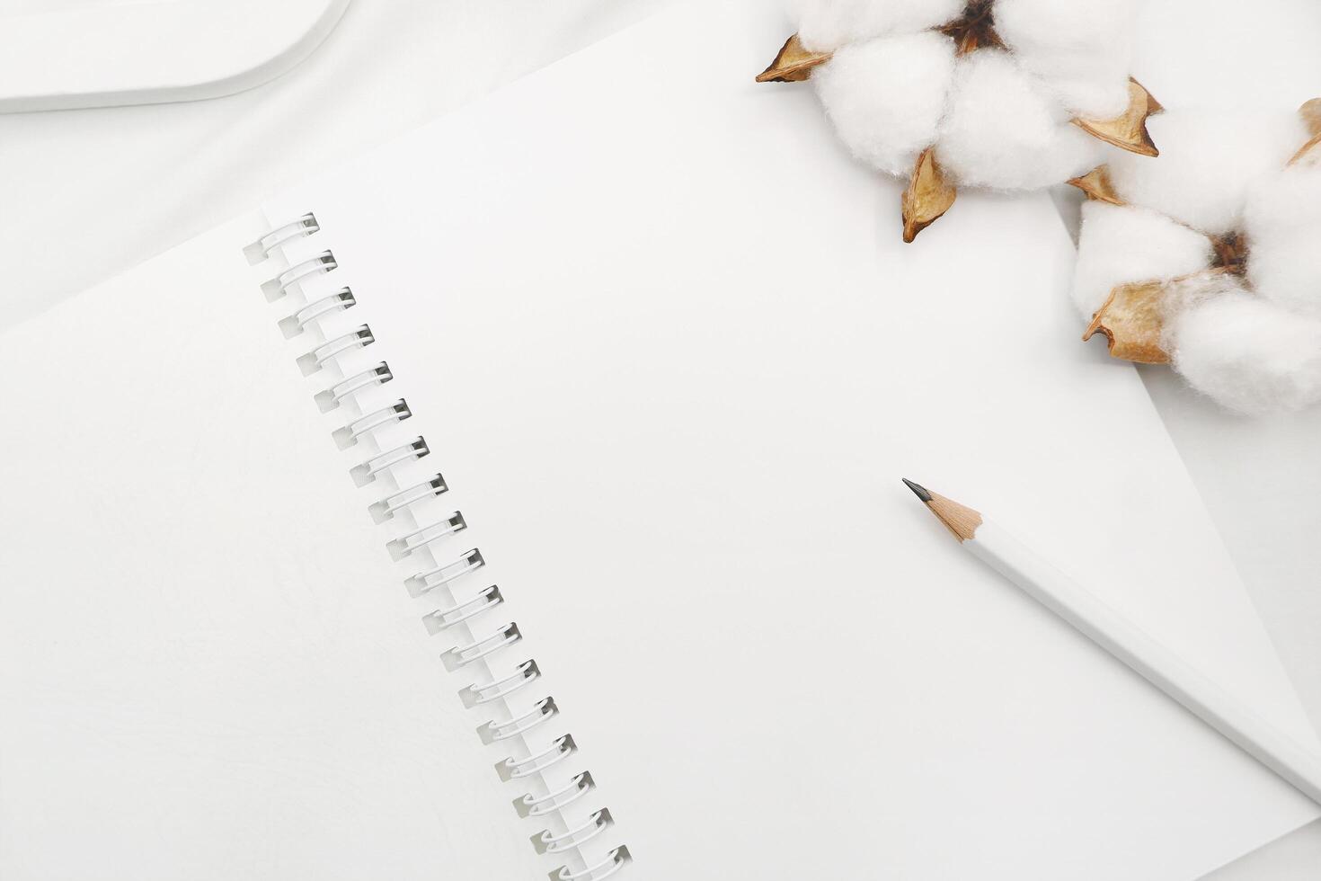 Blank white spiral notebook with white pencil on bed. photo