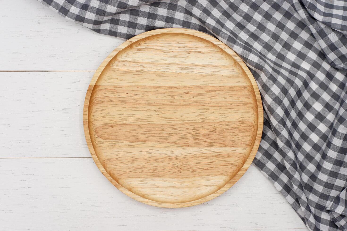 Empty round wooden plate on white wooden table. Top view image. photo