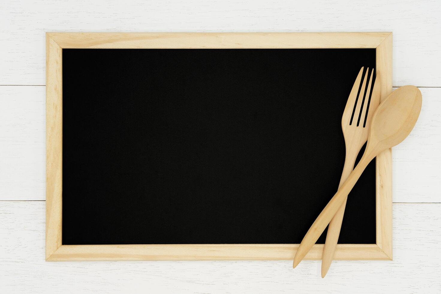 Blank chalkboard with wooden spoon and fork on white wood plank background. Styled stock photography for cookbook, food blog posts and social media content. photo