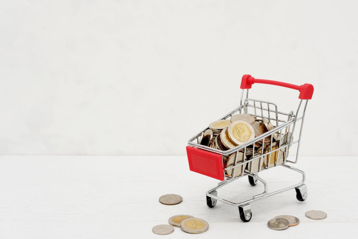 New Thai Baht coins in red miniature shopping cart. Business and finance concept. photo