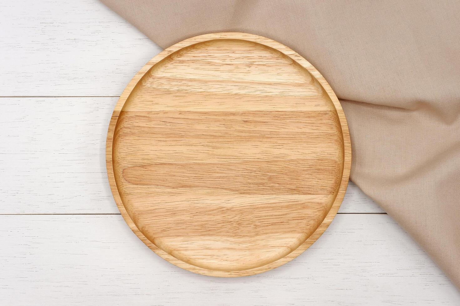 Empty round wooden plate on white wooden table. Top view image. photo