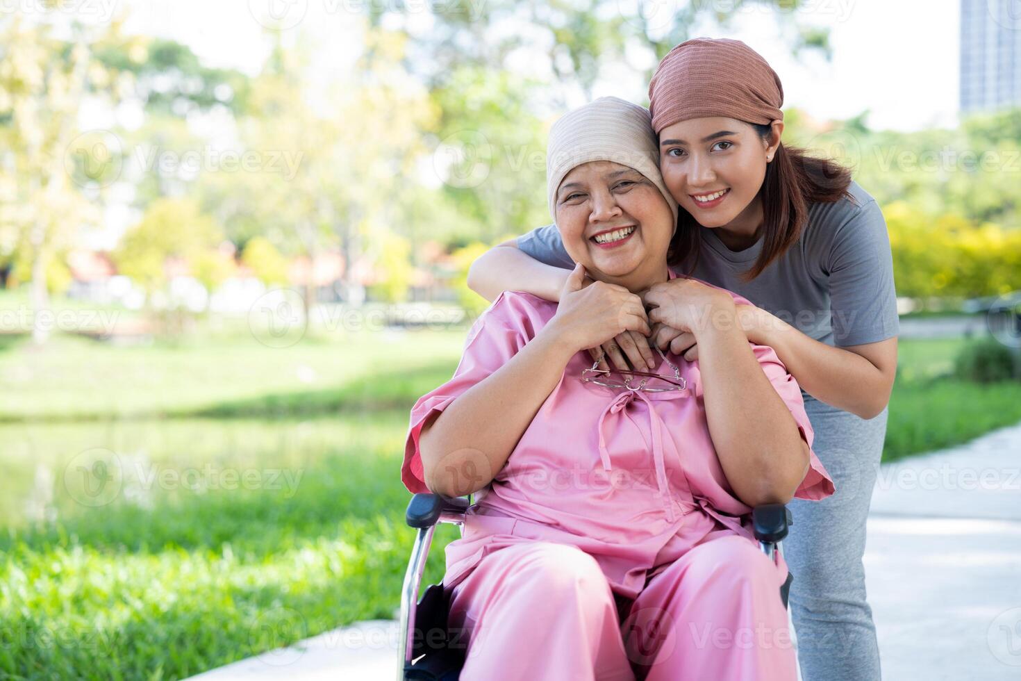 Asian careful caregiver or nurse and woman with cancer is sitting in a wheelchair. in the garden. Concept of happy retirement with care from a caregiver and Savings and senior health insurance. photo