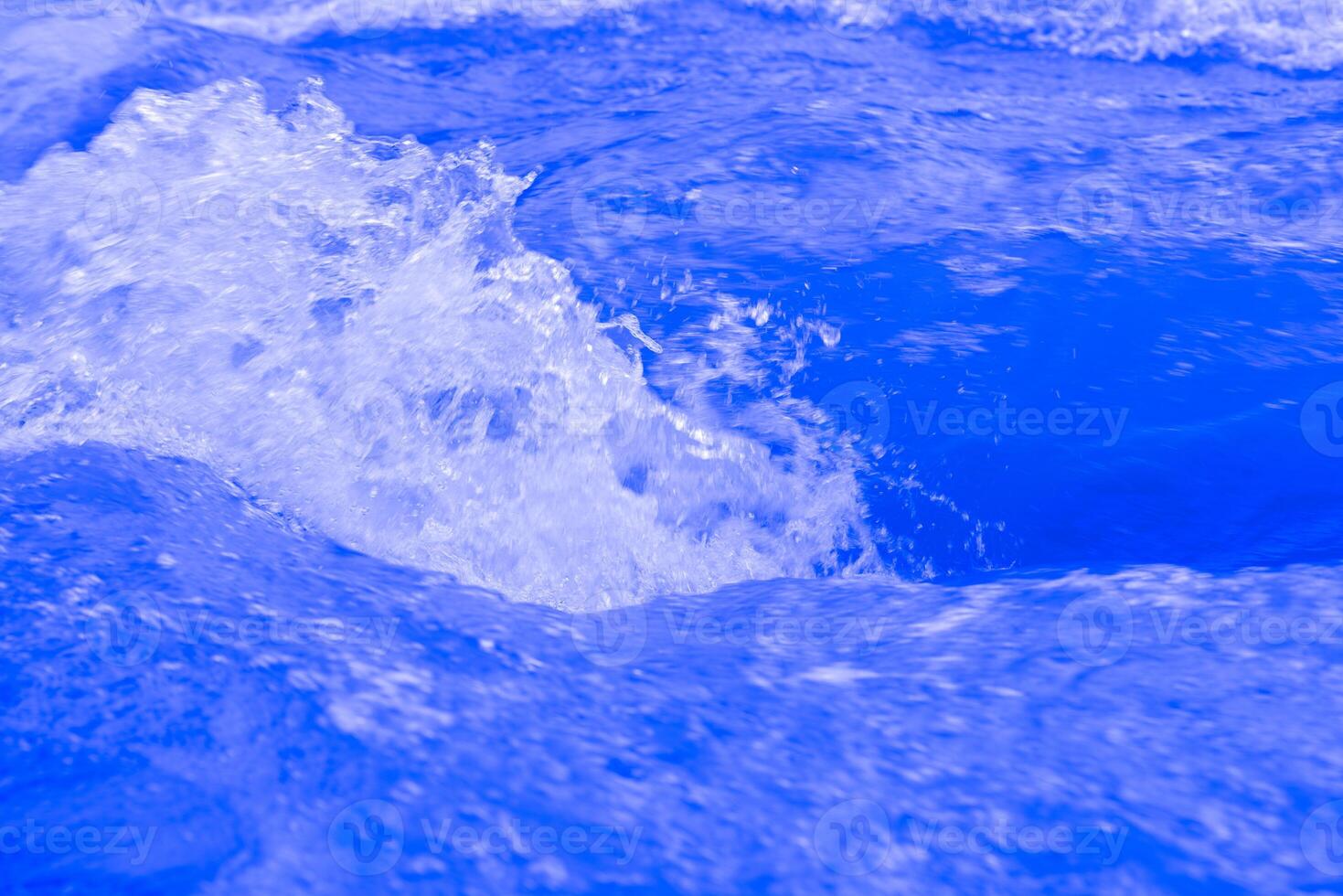 Bluewater waves on the surface ripples blurred. Defocus blurred transparent blue colored clear calm water surface texture with splash and bubbles. Water waves with shining pattern texture background. photo