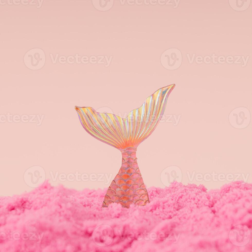 Creative trendy layout made with mermaid diving into pink sand against peachy pink background. Minimal summer concept. Fancy magical summer beach idea. Fantasy mermaid composition. photo
