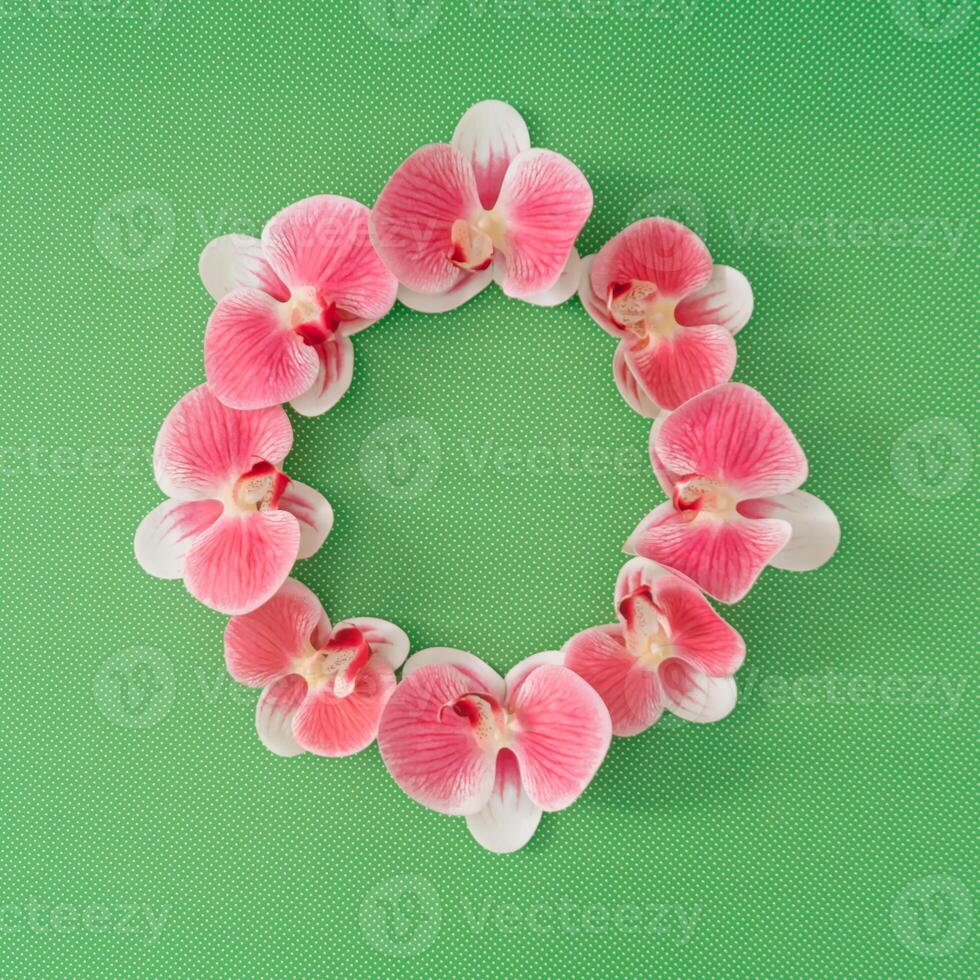 Round frame made of beautiful orchid flowers on green background. Versatile for spring, summer, Mothers Day, weddings. Minimal nature concept. photo