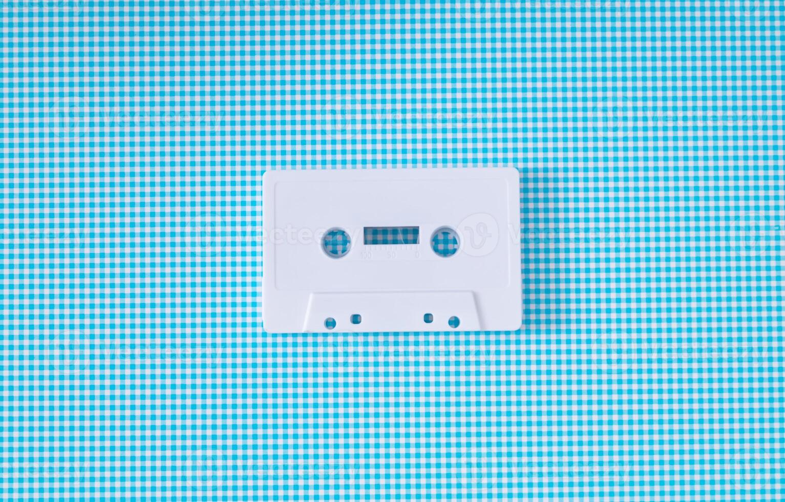 Layout of retro white audio cassette tape on white and blue background. Creative concept of old technology. 80's aesthetic. Vintage audio cassette tape idea. Retro fashion nostalgia. Retro futurism. photo