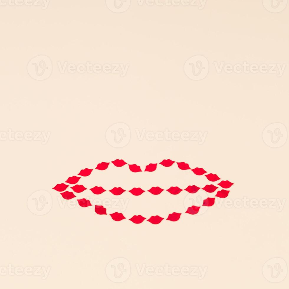 Creative love layout of lips shape made with red lips confetti on light beige background. Minimal love concept with kisses. Romantic style aesthetic idea. photo