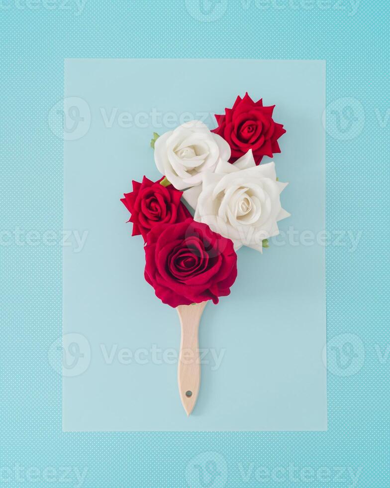 Creative spring and summer composition made with paint brush, red and white roses on blue background. Minimal concept. Trendy paint brush with flowers idea. Flowers aesthetic. Nature flat lay. photo