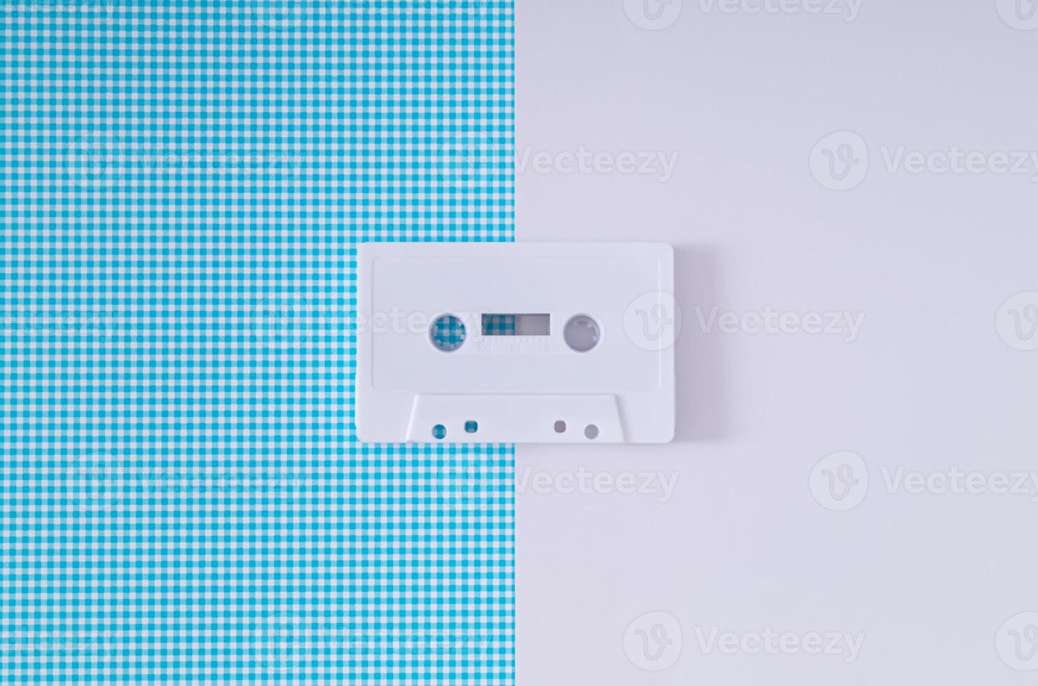 Layout of retro white audio cassette tape on white and blue background. Creative concept of old technology. 80's aesthetic. Vintage audio cassette tape idea. Retro fashion nostalgia. Retro futurism. photo