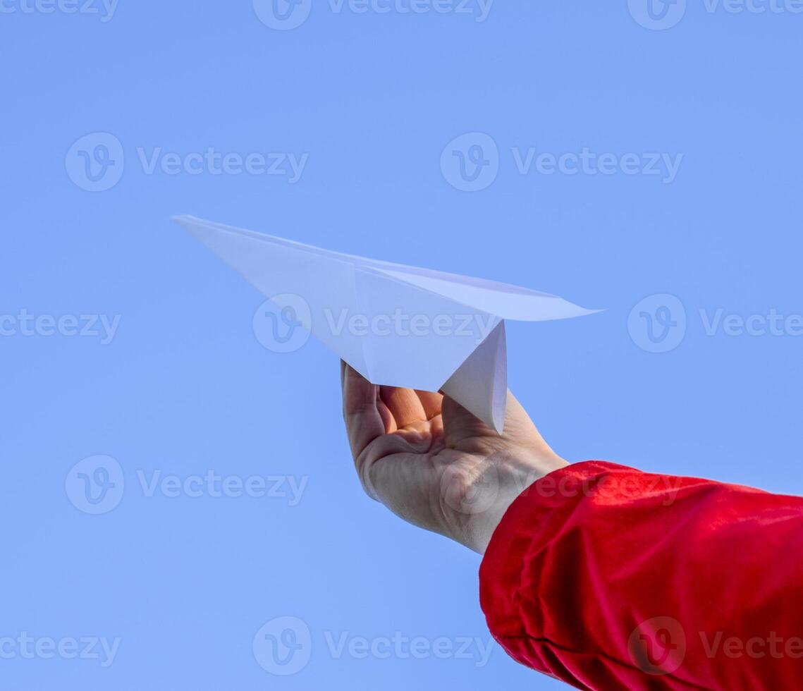 blanco papel avión en mano en contra el cielo. un símbolo de libertad en el Internet foto