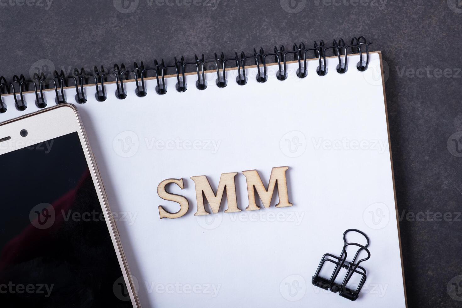 Abbreviation SMM made with wooden letters and phone. Social Media Marketing concept photo