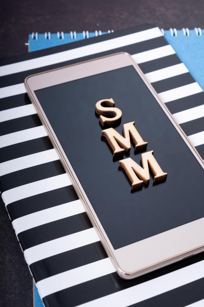 Abbreviation SMM made with wooden letters on phone, top view. Social Media Marketing photo