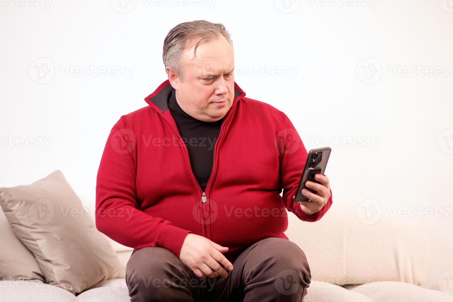 hombre hablando o acecho alguna cosa en su teléfono mientras sentado en el sofá foto