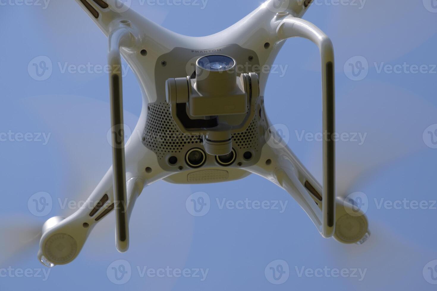 Drone DJI Phantom 4 in flight. Quadrocopter against the blue sky with white clouds. The flight of the copter in the sky. photo
