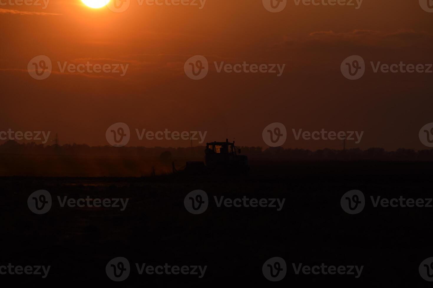 Tractor plowing plow the field on a background sunset. tractor silhouette on sunset background photo
