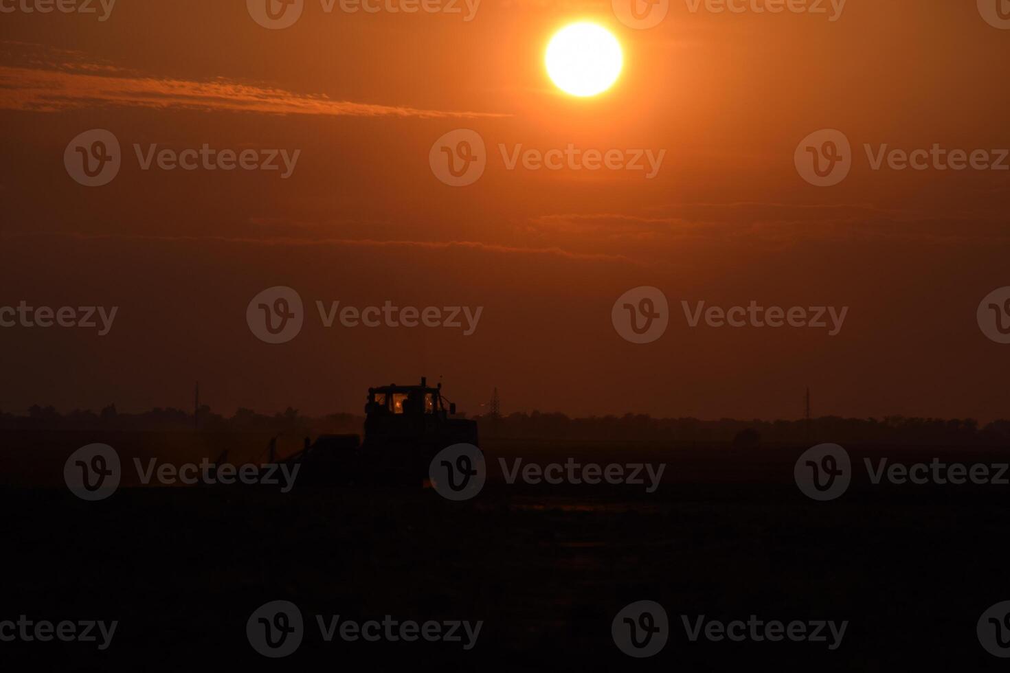 Tractor plowing plow the field on a background sunset. tractor silhouette on sunset background photo