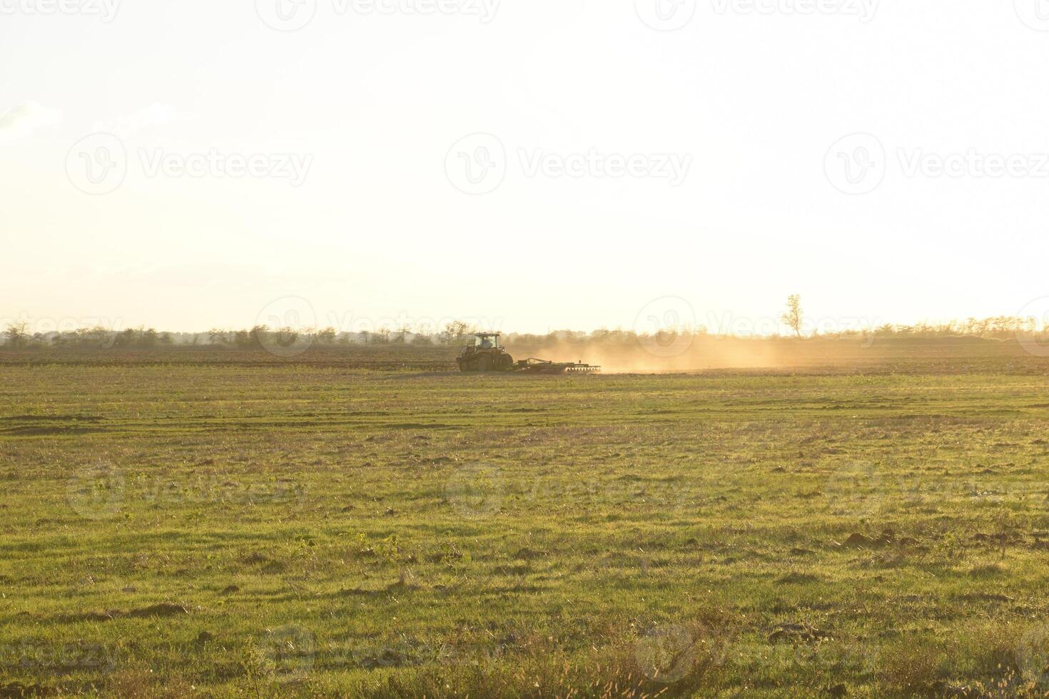 Tractor at sunset plow plow a field. Tilling the soil in the fall after harvest. The end of the season photo